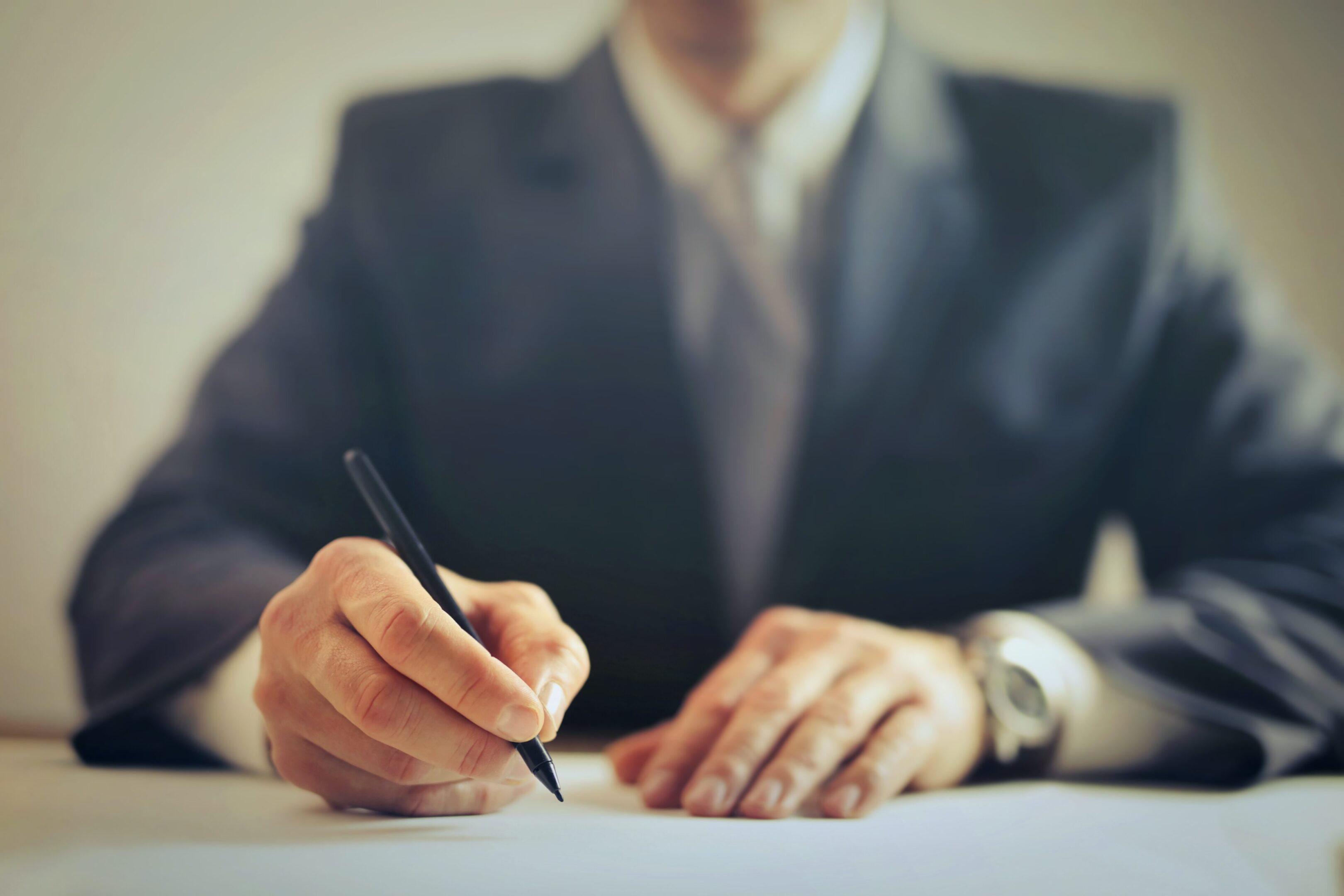 A man in a suit writing on paper.